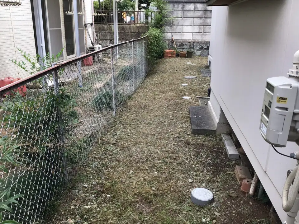 草が短く刈られた建物脇の通路